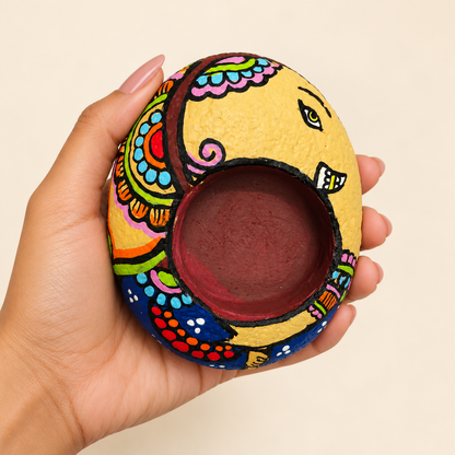 Ganesh: Joyful Bloom hand-painted natural pebble tealight holder, shown in hand for scale