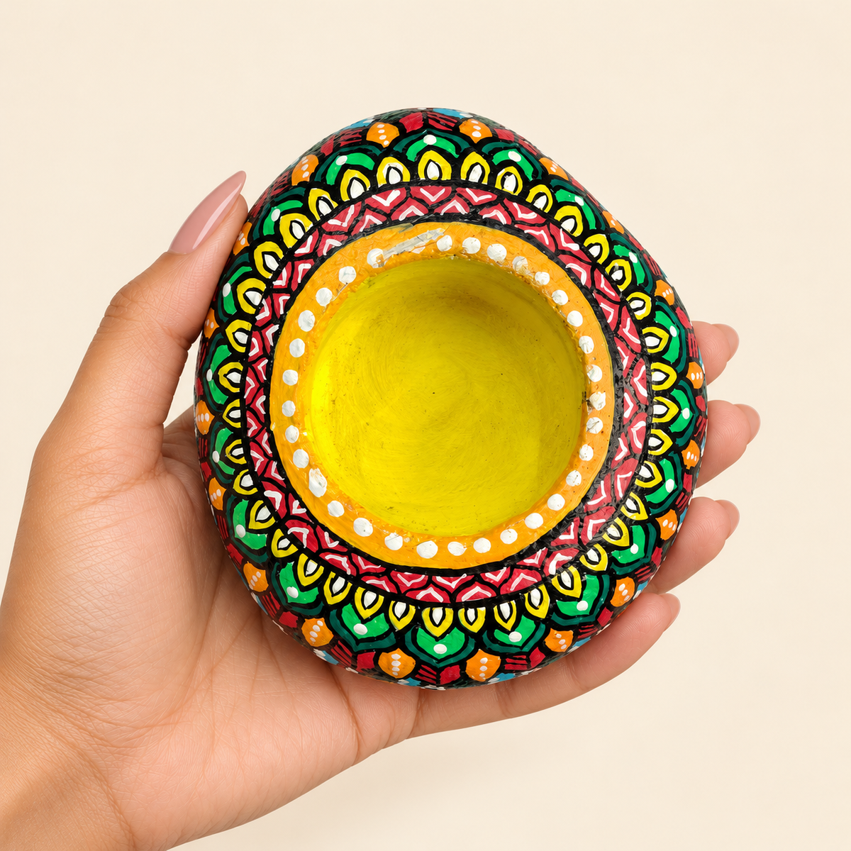 Mandala: Saffron Bloom hand-painted natural pebble tealight holder, shown in hand for scale