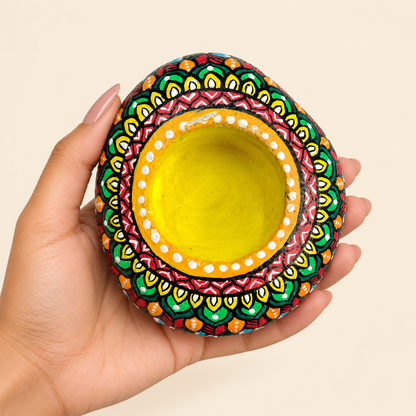 Mandala: Saffron Bloom hand-painted natural pebble tealight holder, shown in hand for scale