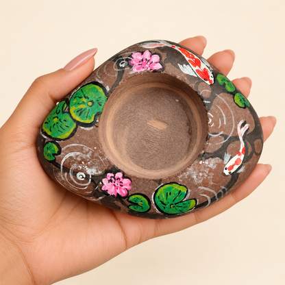 Lotus Pond: Koi Garden hand-painted natural pebble tealight holder, shown in hand for scale