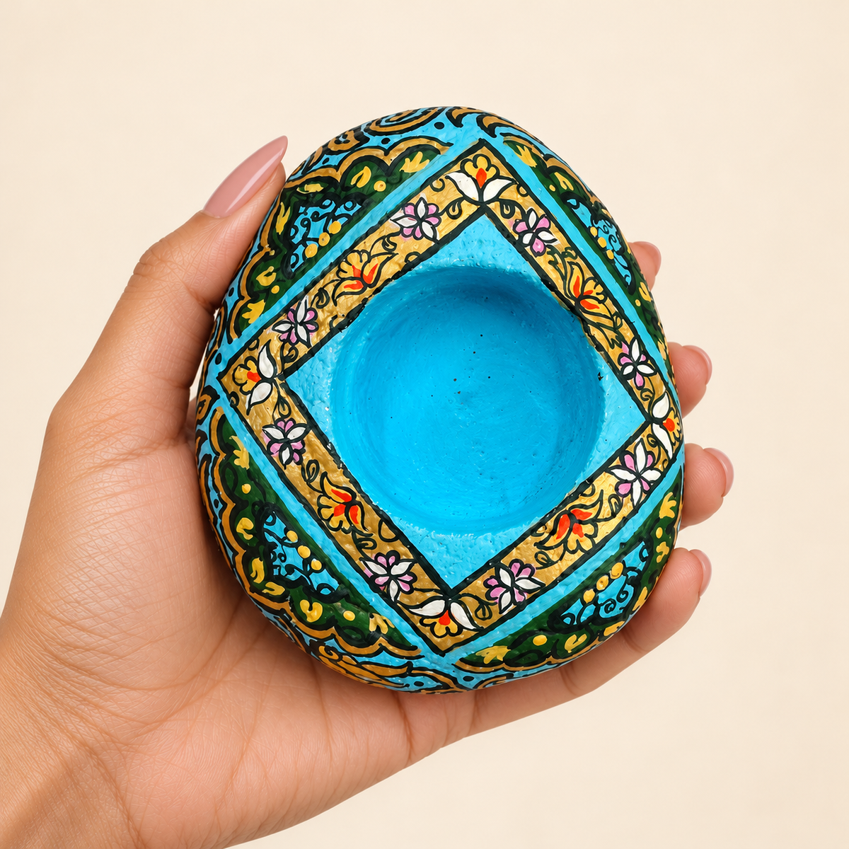 Azure Diamond: Floral Frame hand-painted natural pebble tealight holder, shown in hand for scale