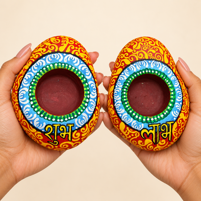 Shubh Labh: Azure Mandala hand-painted natural pebble tealight holder, shown in hand for scale