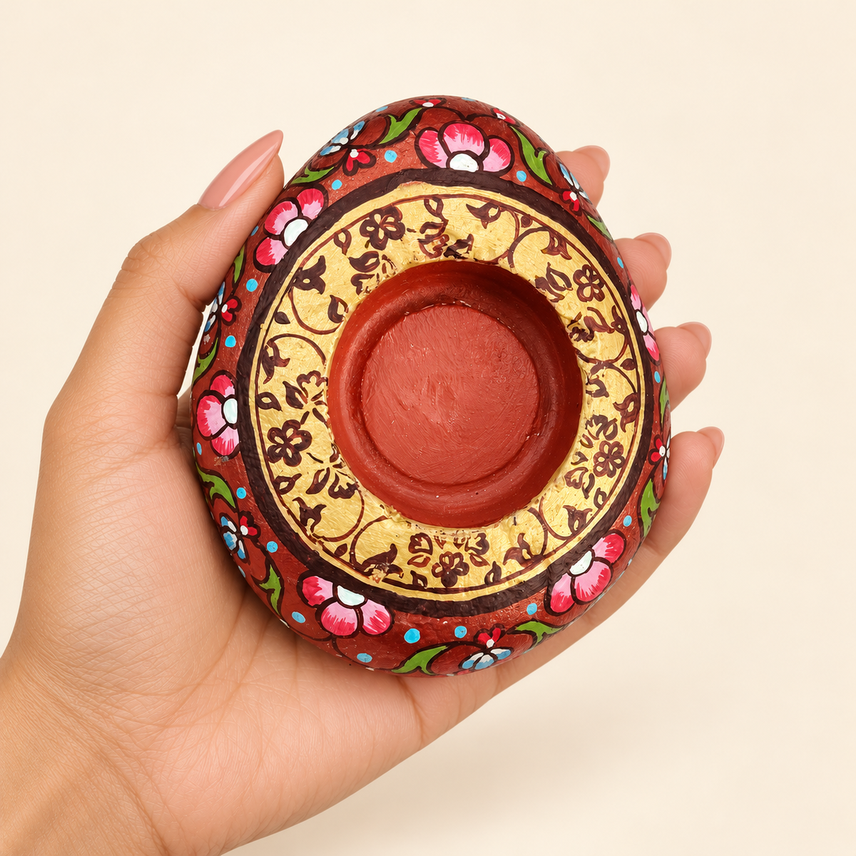 Gilded Florals: Terracotta Charm hand-painted natural pebble tealight holder, shown in hand for scale