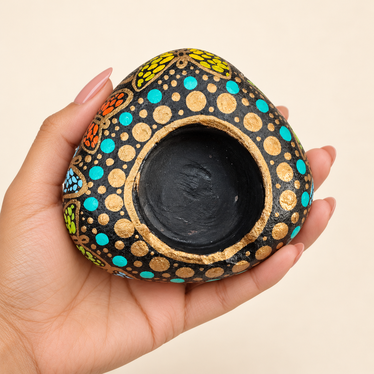 Gilded Dots: Night Garden hand-painted natural pebble tealight holder, shown in hand for scale