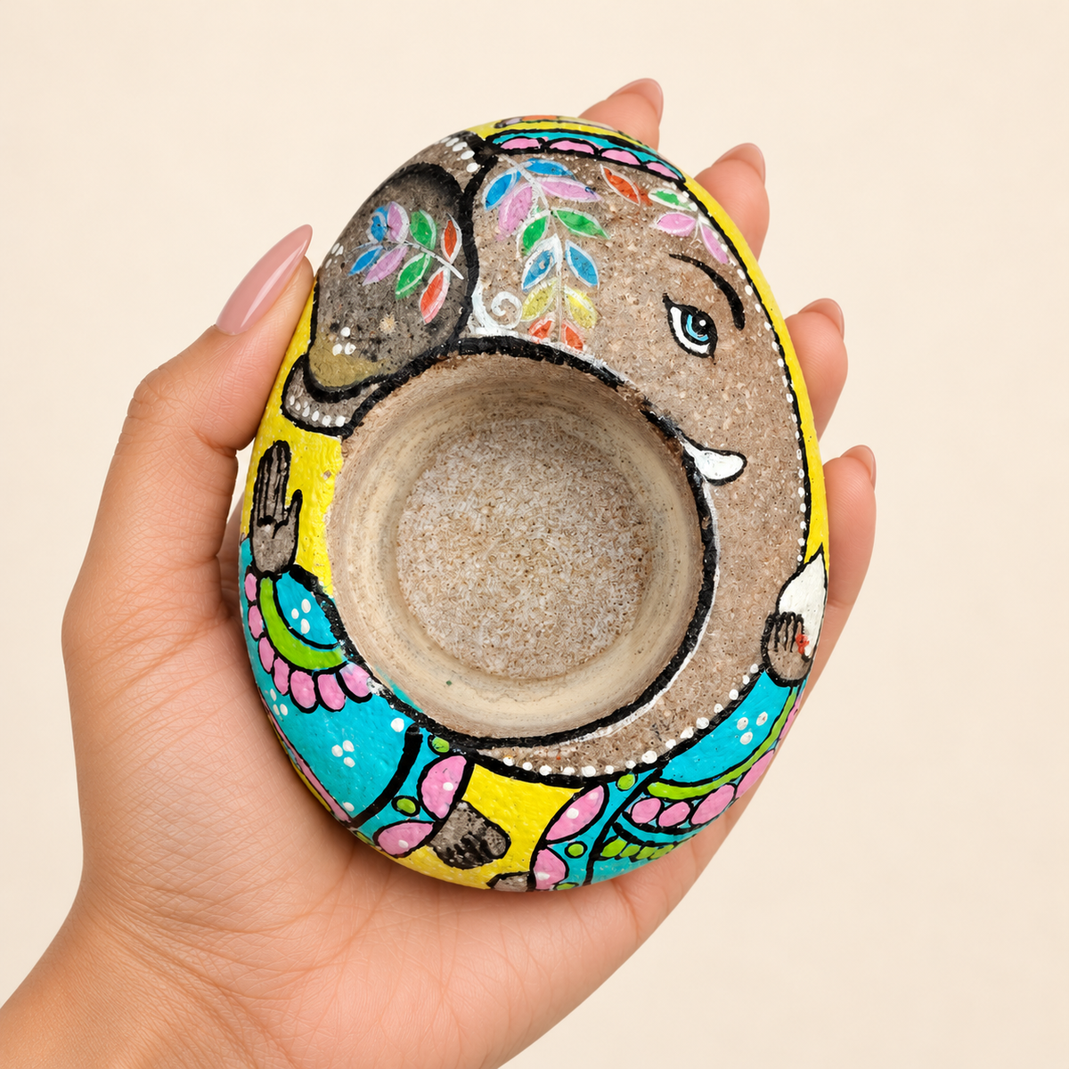 Ganesh: Earth and Petals hand-painted natural pebble tealight holder, shown in hand for scale