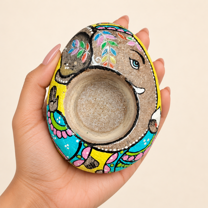 Ganesh: Earth and Petals hand-painted natural pebble tealight holder, shown in hand for scale