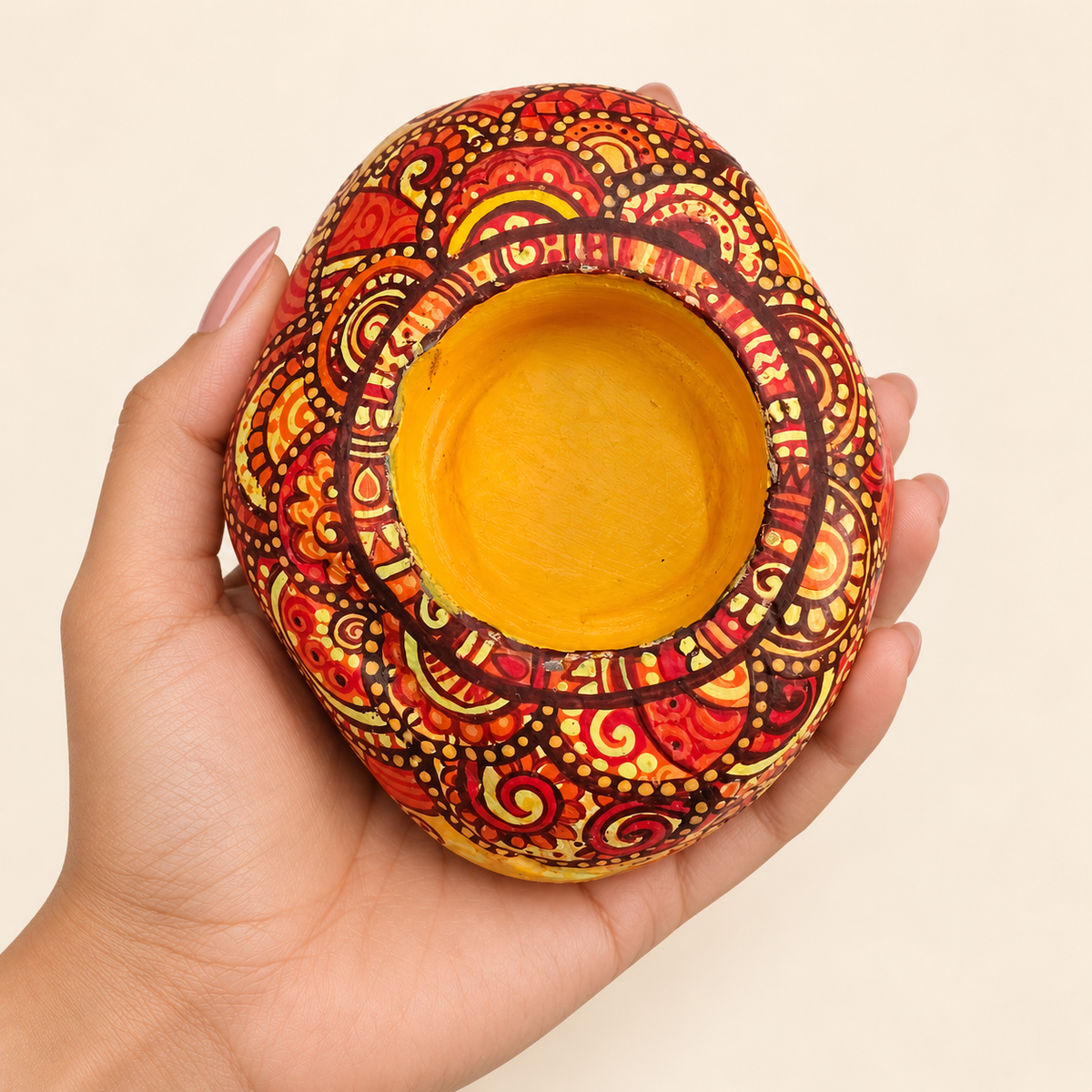 Mehendi Mandala: Sunlit Amber hand-painted natural pebble tealight holder, shown in hand for scale