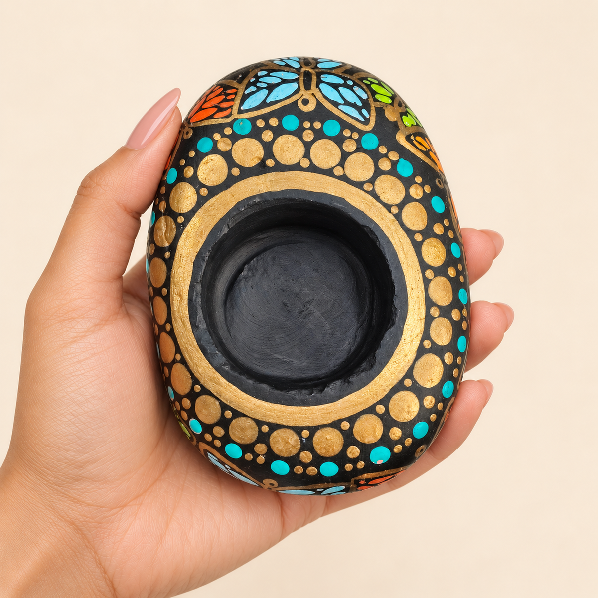 Butterfly Mandala: Golden Turquoise hand-painted natural pebble tealight holder, shown in hand for scale