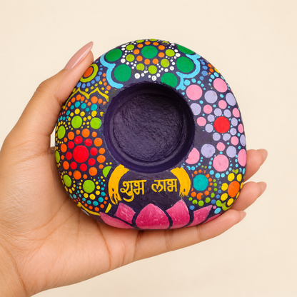 Shubh Labh: Kaleidoscope Bloom hand-painted natural pebble tealight holder, shown in hand for scale
