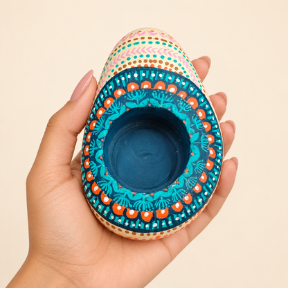 Peacock Fan: Lagoon Blue hand-painted natural pebble tealight holder, shown in hand for scale
