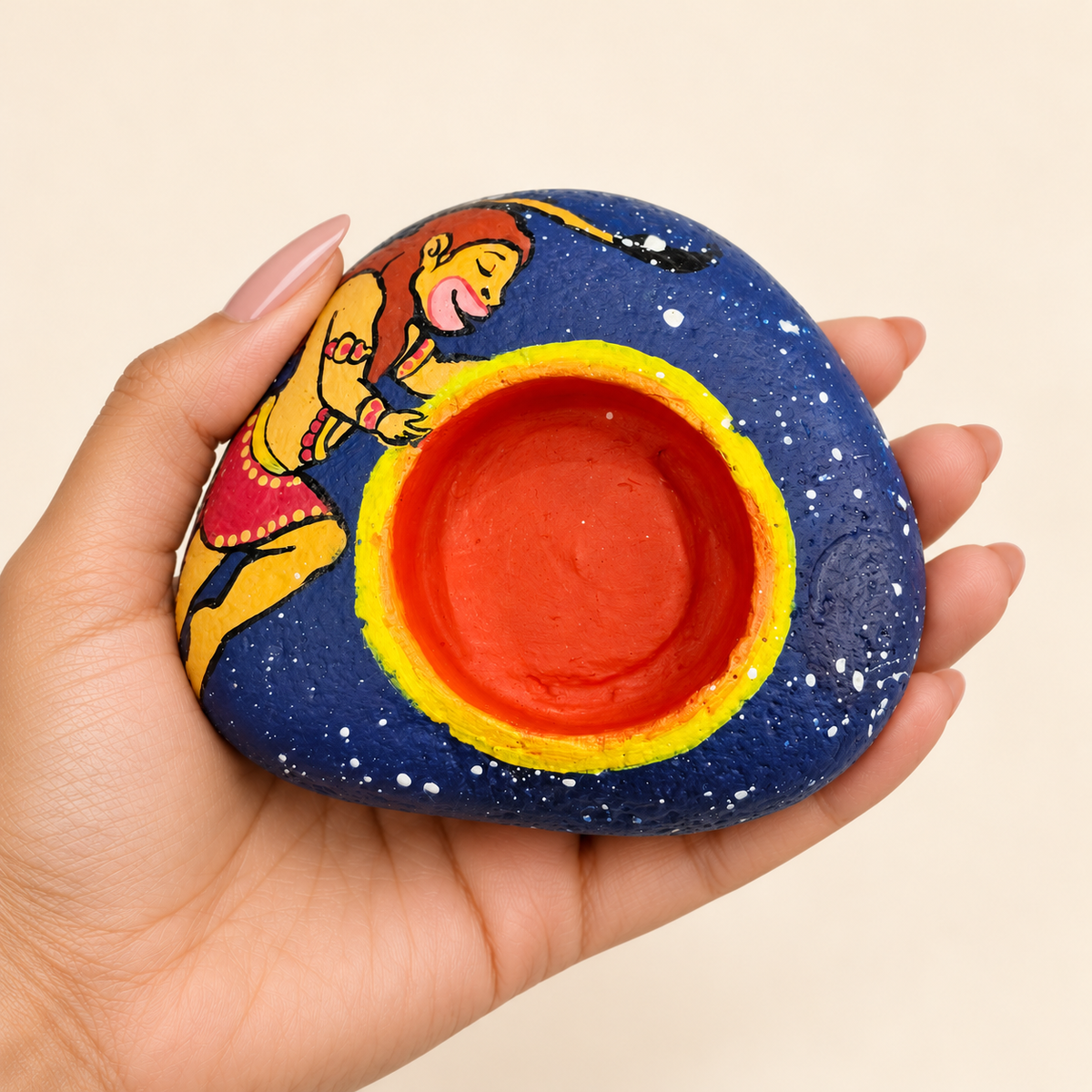 Hanuman: Starry Devotion hand-painted natural pebble tealight holder, shown in hand for scale