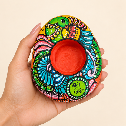 Parrot: Teal Celebration hand-painted natural pebble tealight holder, shown in hand for scale
