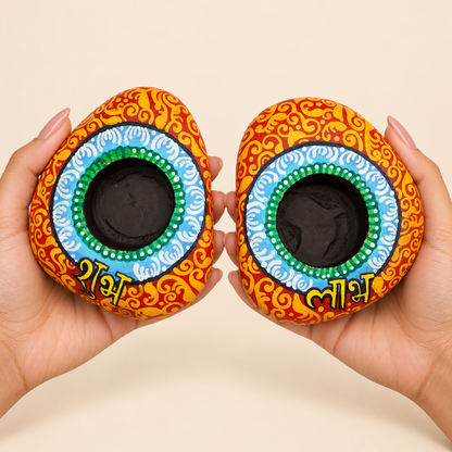 Shubh Labh: Sky Mandala hand-painted natural pebble tealight holder, shown in hand for scale