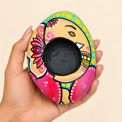 Ganesh: Rose and Sky hand-painted natural pebble tealight holder, shown in hand for scale