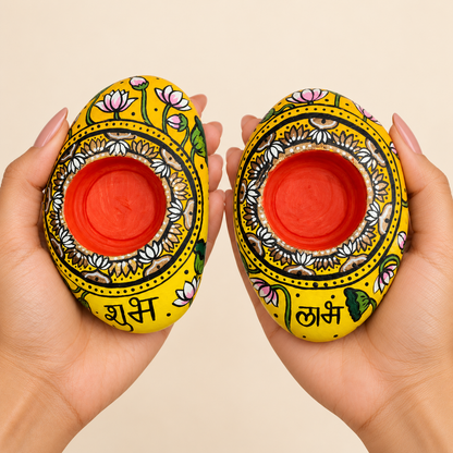 Shubh Labh: Golden Lotus hand-painted natural pebble tealight holder, shown in hand for scale