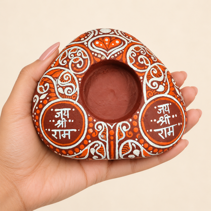 Jai Shri Ram: Terracotta Devotion hand-painted natural pebble tealight holder, shown in hand for scale
