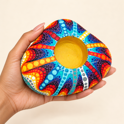 Sunburst: Rainbow Tide hand-painted natural pebble tealight holder, shown in hand for scale