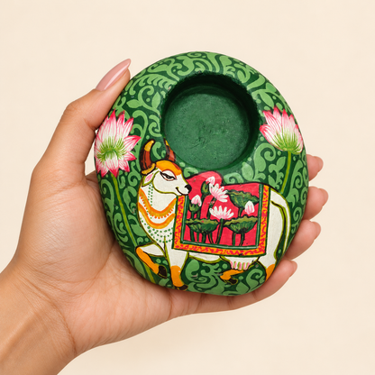Kamdhenu: Emerald Garden hand-painted natural pebble tealight holder, shown in hand for scale