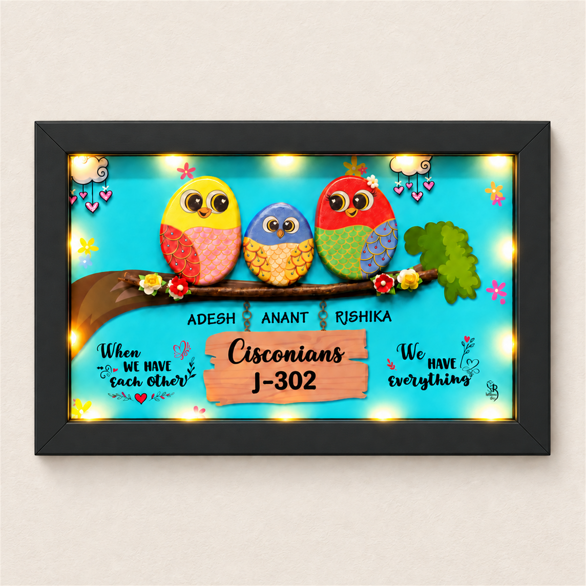 Celebrate Togetherness with Unique Family Pebble Art: three colourful birds in a family nameboard, black frame, on a beige background