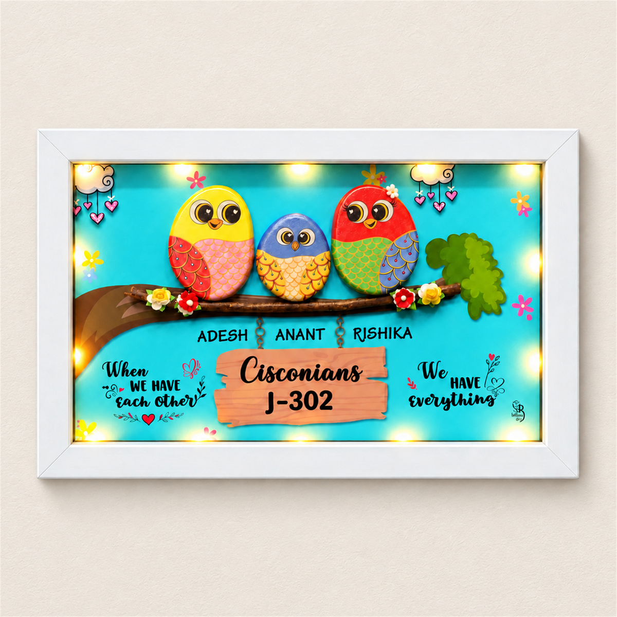 Celebrate Togetherness with Unique Family Pebble Art: three colourful birds in a family nameboard, white frame, on a beige background