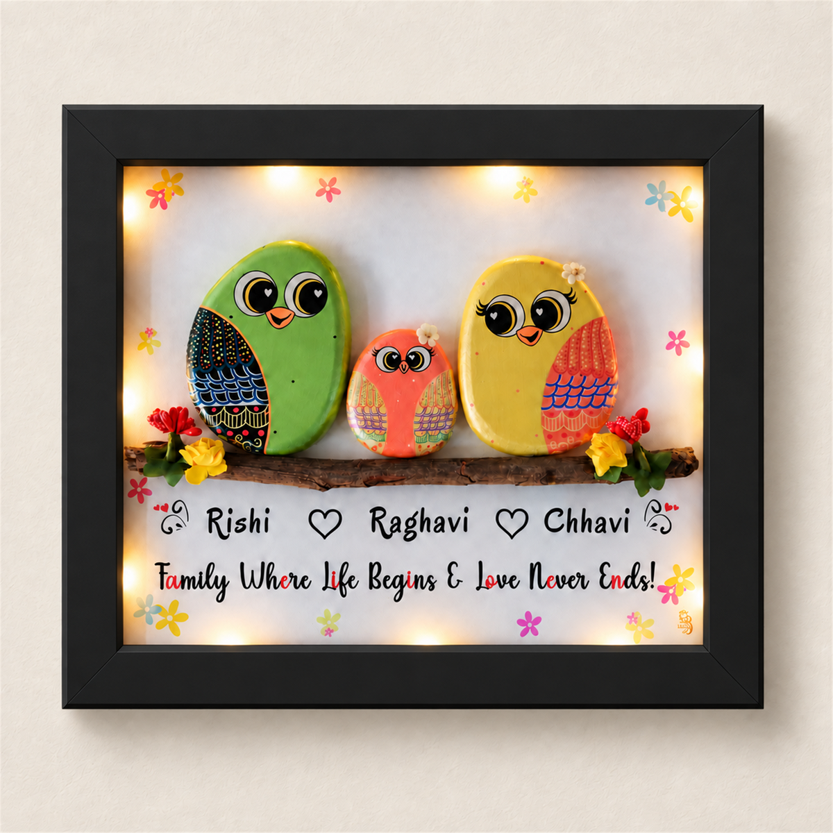 Happily Ever After Pebble Art: three colourful little birds on a flower-trimmed branch, black frame, on a beige background