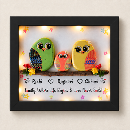 Happily Ever After Pebble Art: three colourful little birds on a flower-trimmed branch, black frame, on a beige background