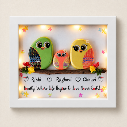 Happily Ever After Pebble Art: three colourful little birds on a flower-trimmed branch, white frame, on a beige background