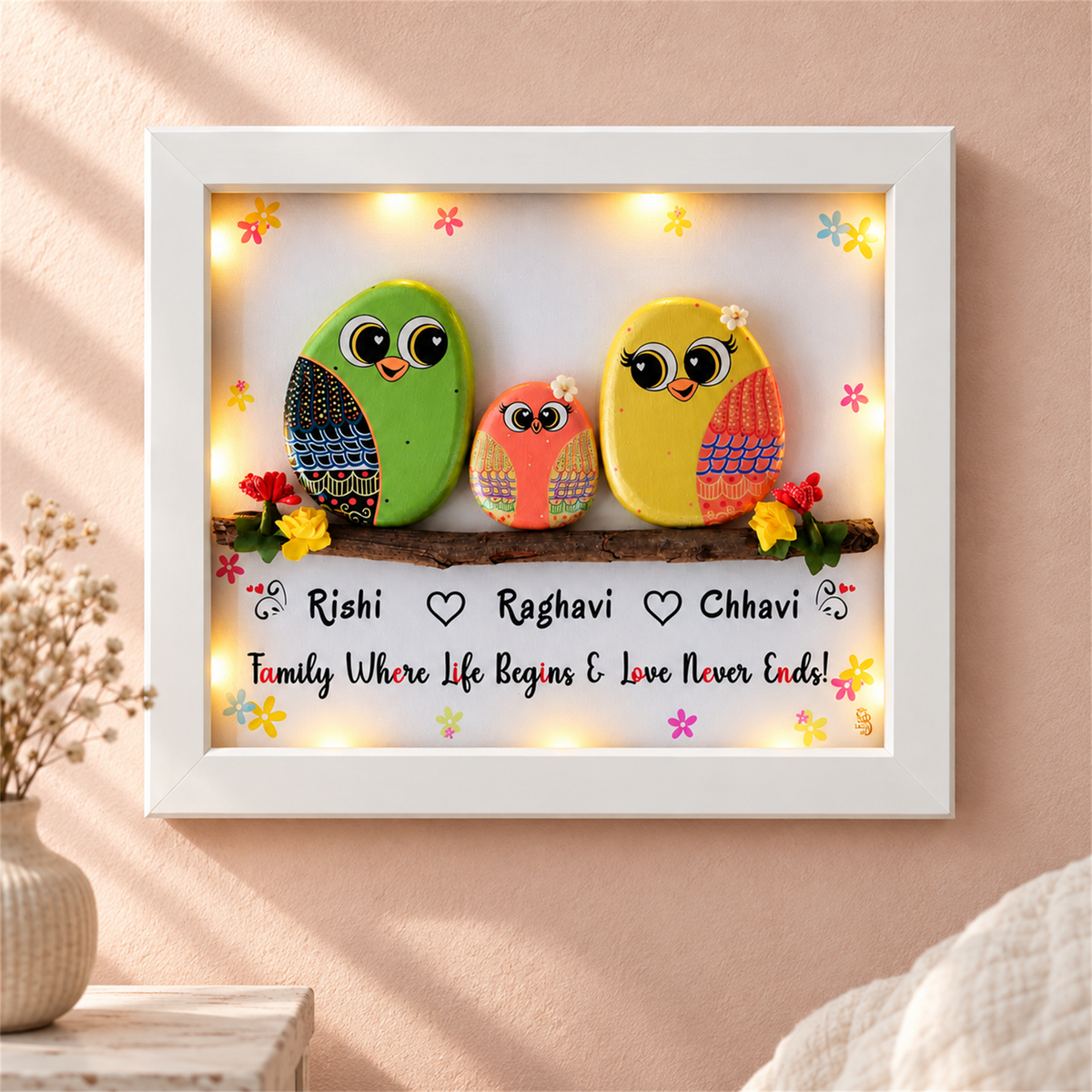 Happily Ever After Pebble Art: three colourful little birds on a flower-trimmed branch, white frame, in a home setting