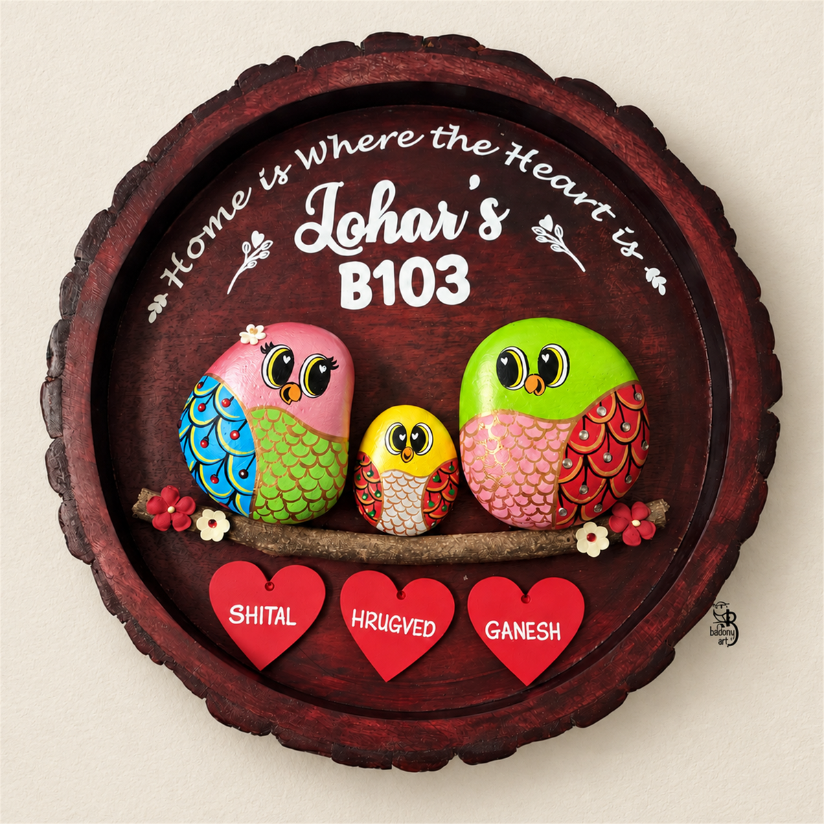 Joy Junction Pebble Art: three colourful birds with red heart name tags on dark round wood, on a beige background