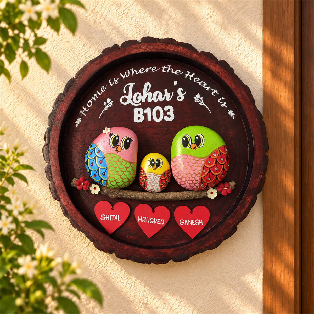 Joy Junction Pebble Art: three colourful birds with red heart name tags on dark round wood, in a home setting